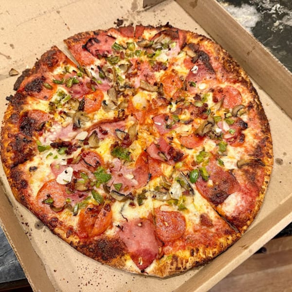Karl's Place Pizza with pepperoni, ham, mushrooms, and green peppers in a cardboard box.