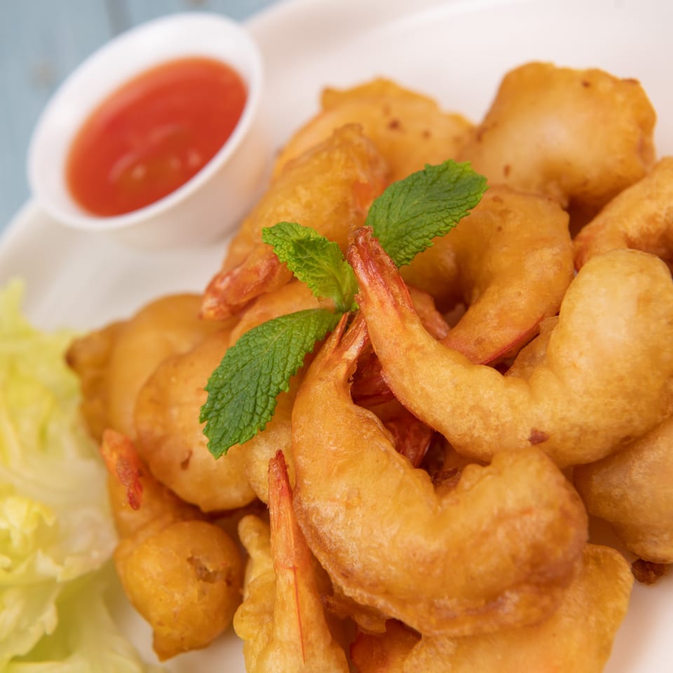 Golden-fried shrimp with a sprig of mint, lettuce, and a side of red dipping sauce.